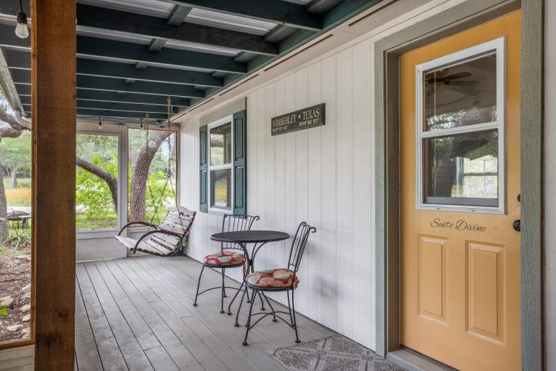 Suite Divine Entrance Background is a porch swing. Foreground is a bistro table set for two and the private entrance to Suite Divine on the inn's front porch.